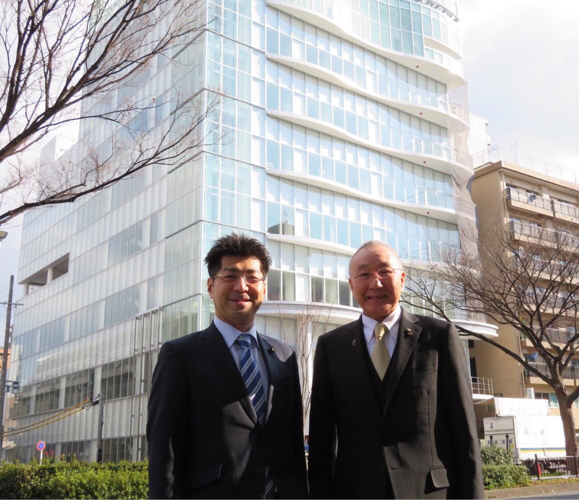 山本幸助理事長と、今春オープン予定の組合の美容専門学校新校舎の前で
